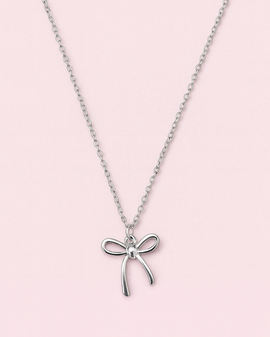 Silver necklace with a bow pendant on a pink background